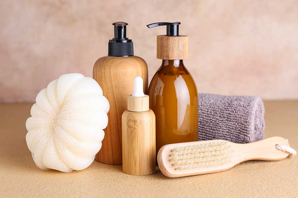 Bottles of cosmetic products, massage brush, sponge and towel