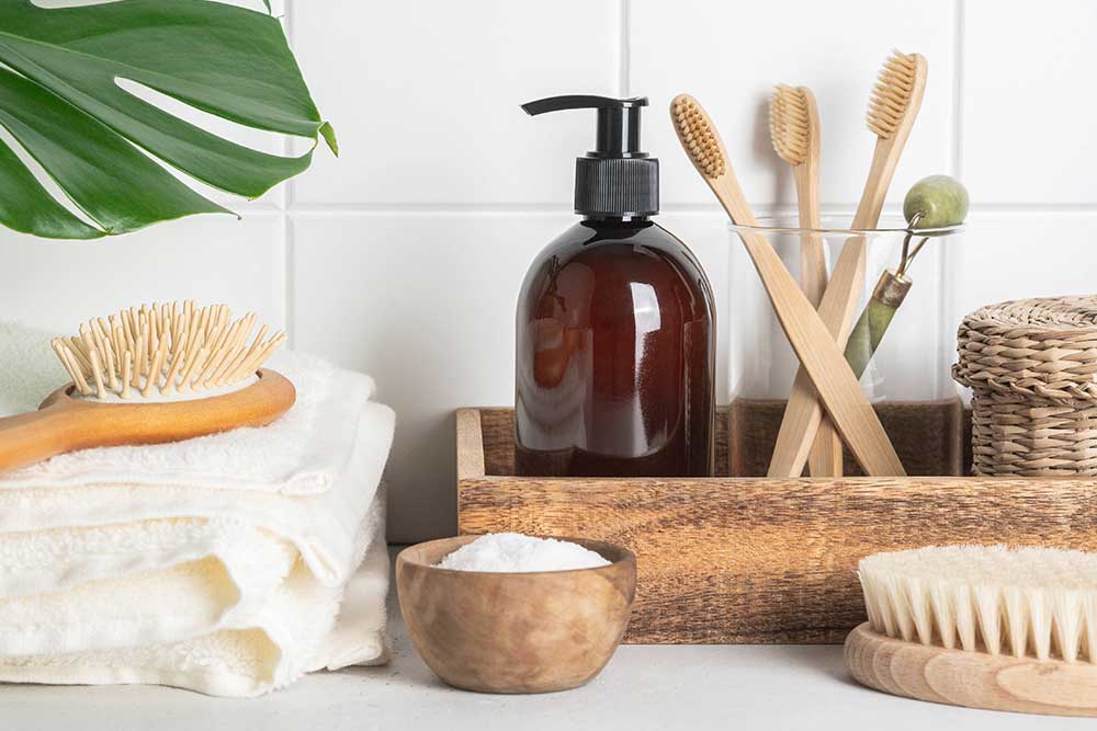 White bath background front view with cosmetic bottle, bath accessories and green leaf on white shelf and wall tiles